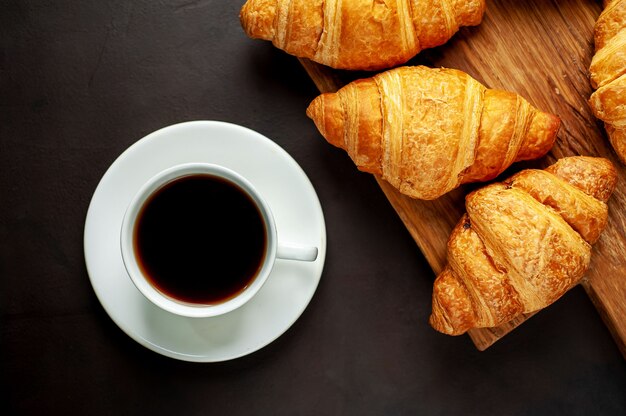 coffee and croissants on wooden cutting board