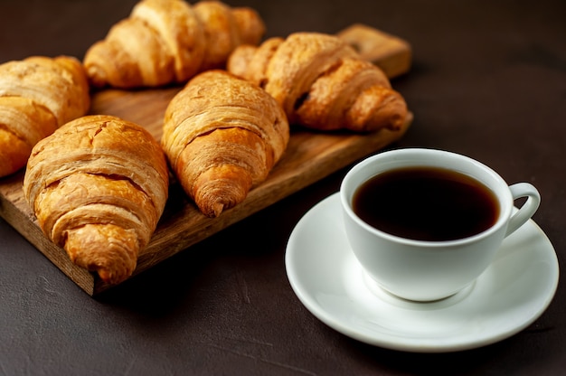 木製のまな板にコーヒーとクロワッサン