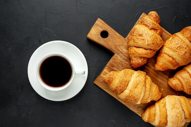 coffee and croissants on wooden cutting board