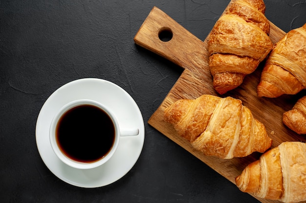 coffee and croissants on wooden cutting board