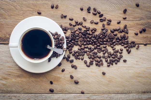 木の背景にコーヒーカップと豆コーヒー