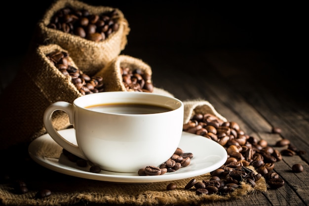 Tazza di caffè e fagioli su uno sfondo rustico.