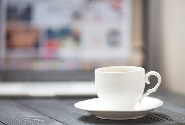 Coffee Cup on the black table on blurred laptop background for Business Concept.