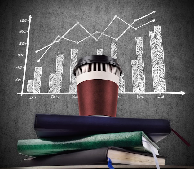 Coffee cup on books and drawing stock chart