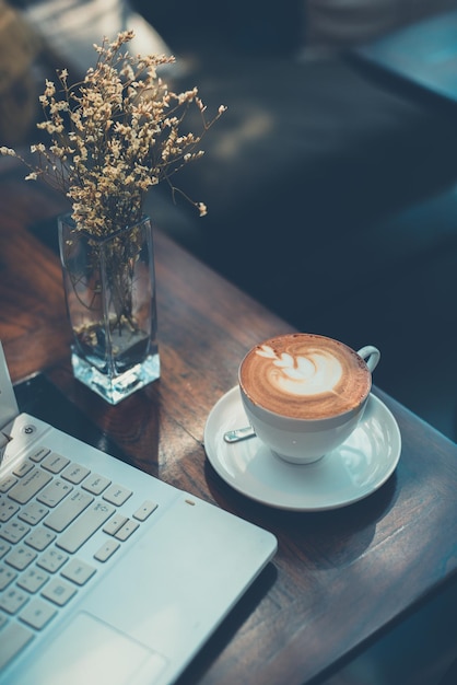 coffee cup by laptop on wooden table