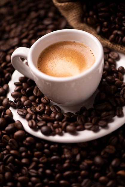 Coffee cup close-up over dark roasted coffee beans