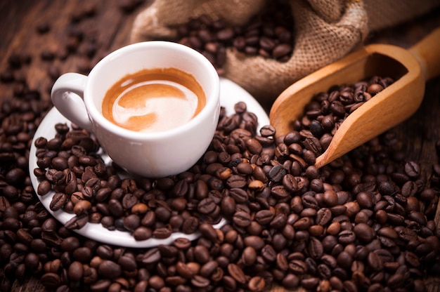 Primo piano della tazza di caffè sopra i chicchi di caffè tostati scuri