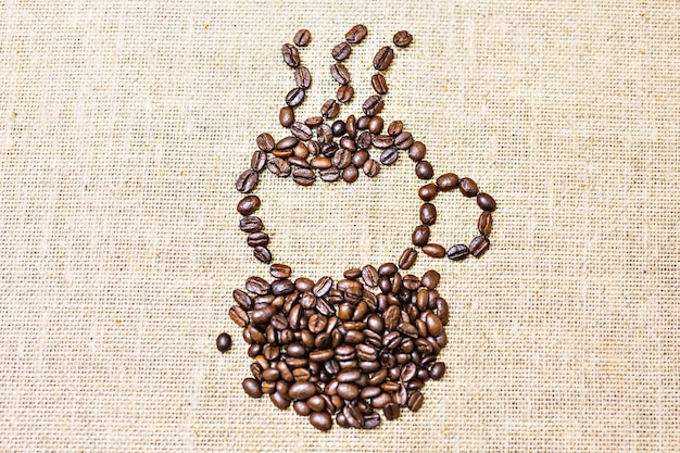 Coffee cup of coffee beans on burlap texture