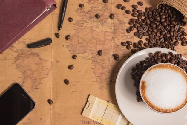 coffee cup and coffee beans on table with big map background on tab table