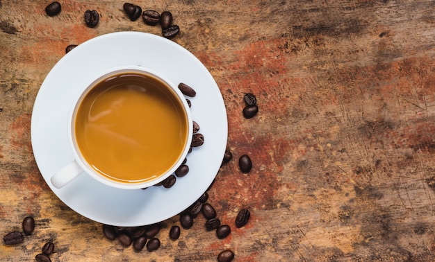 Coffee in a cup and coffee beans on the table with copy space