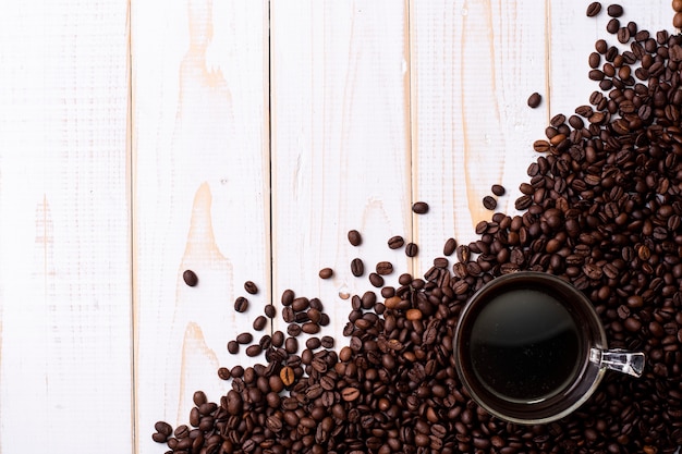 Coffee cup and coffee beans on white wooden table 