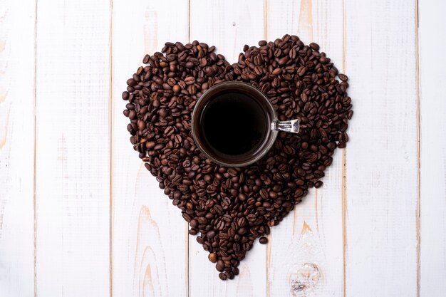 Coffee cup and coffee beans on white wooden table 