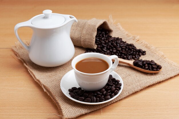 Coffee cup and coffee beans on wood plank background