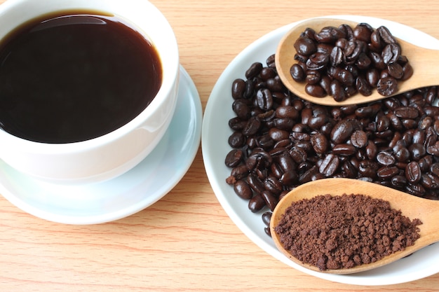 Tazza di caffè e chicchi di caffè sul tavolo di legno.