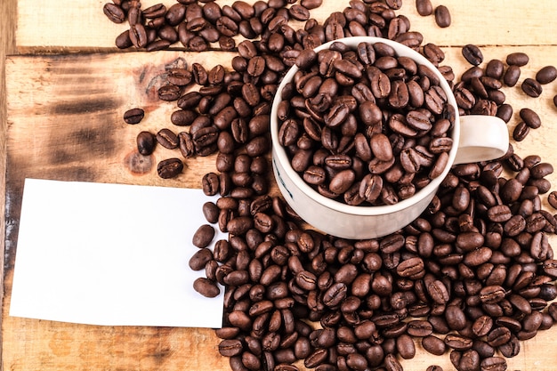 Coffee cup and coffee beans on wooden background. Top view copy space