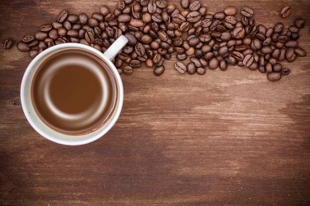 Кофейная чашка и кофейные бобы на деревянном фоне