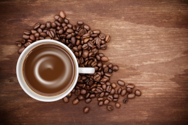 Coffee cup and coffee beans on wooden background