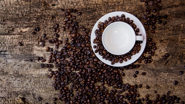 Coffee cup and coffee beans on wooden table. Dark table.