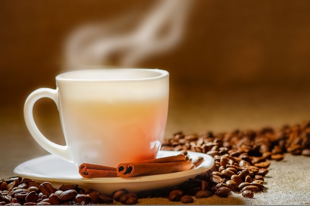 Coffee cup and coffee beans on a wooden table and sack