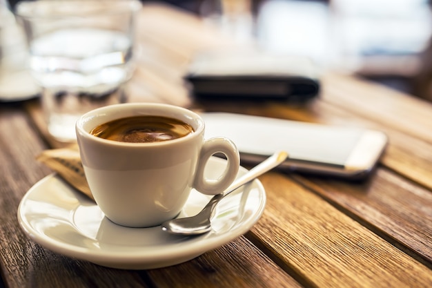 コーヒー。レストランのコーヒーのテーブルの上のコーヒー携帯電話のカップ
