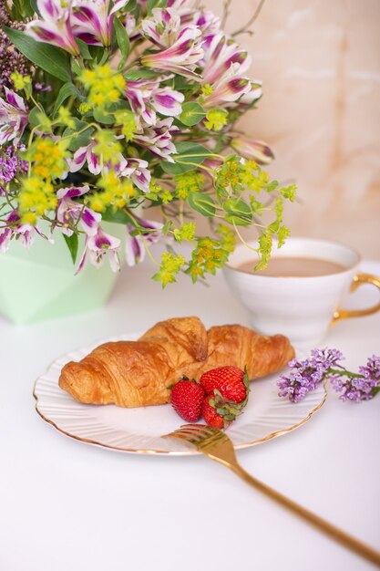 Coffee cup and croissant with fresh strawberry