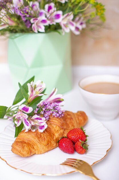 Coffee cup and croissant with fresh strawberry