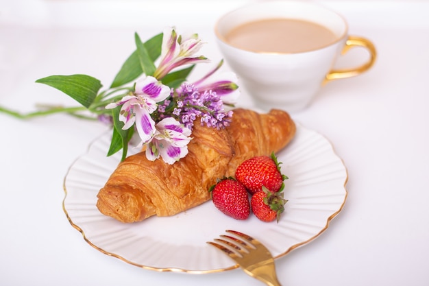 Coffee cup and croissant with fresh strawberry