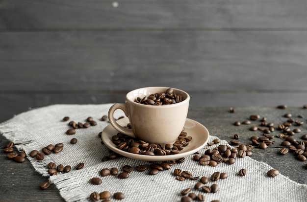 新鮮なアラビカ種またはロブスタ種のコーヒー豆が散りばめられたコーヒーカップで満たされた