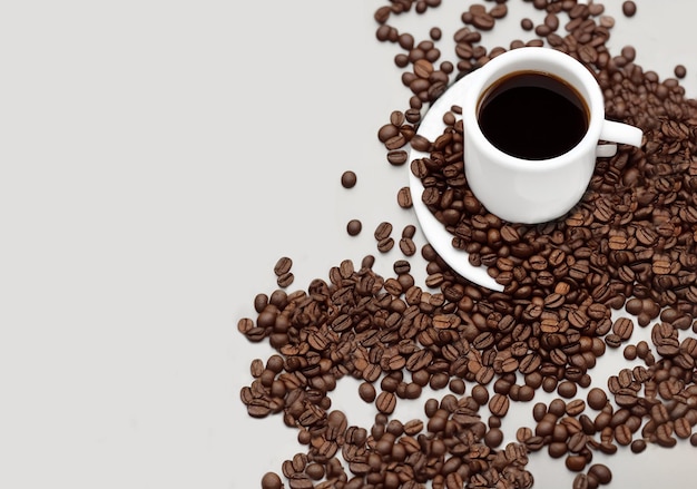 Coffee cup filled with coffee beans on a background of roasted arabica coffee beans