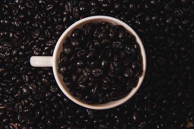 Coffee cup filled with coffee beans on coffee bean surface Copy space Selective focus