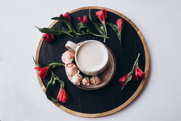 Coffee cup and flowers on dark wooden table in cafe