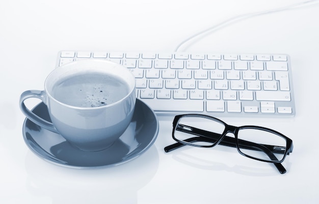 Coffee cup glasses and computer keyboard