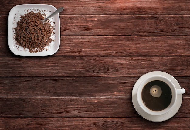 Coffee in cup and ground coffee on wooden table top view