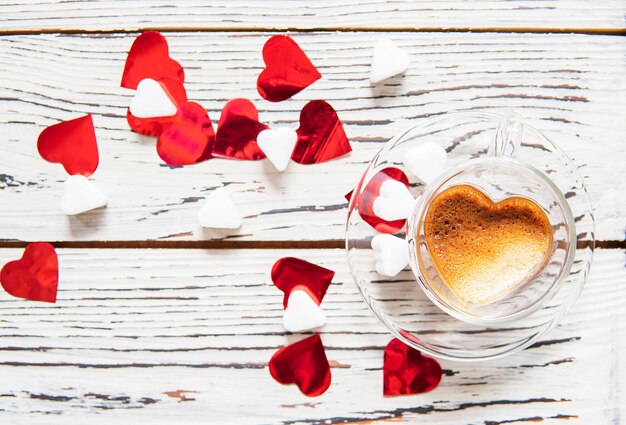 Coffee cup heart shaped with confetti and sugar on white wood. 