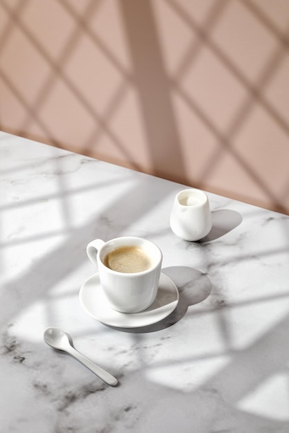 Coffee cup hot drink in a mug Beige and marble background with window shadow Sunny Cappuccino in cup