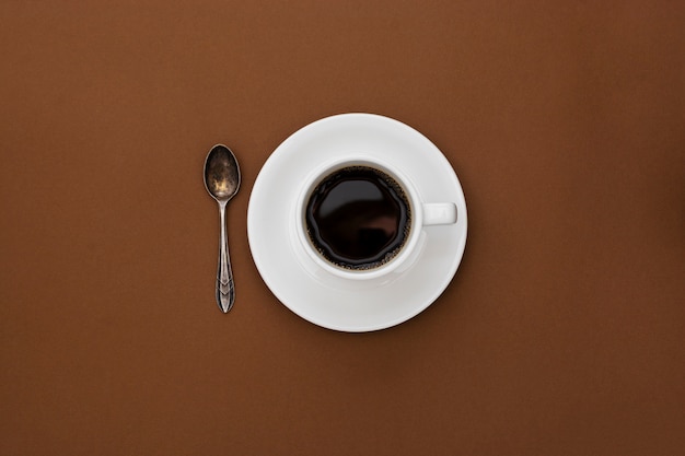 Coffee cup isolated on brown table. Top view, flat lay black coffee drink with copy space.