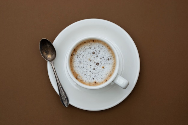 Coffee cup isolated on brown table. Top view, flat lay black coffee drink with copy space.