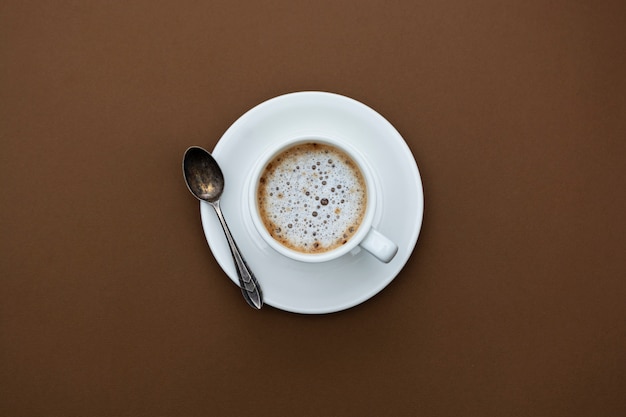 Кофейная чашка изолированная на коричневой таблице. Вид сверху, плоский лежал черный кофе напиток с копией пространства.
