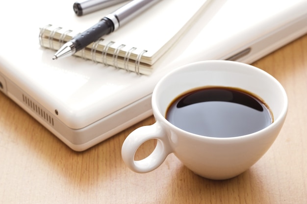 Coffee cup and laptop on wooden background.