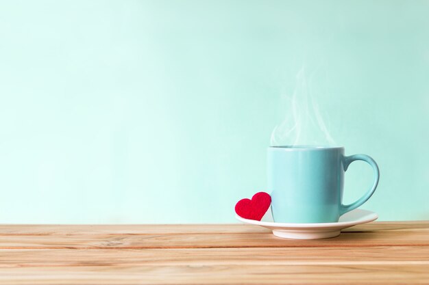 Coffee cup mug with red heart shape on wooden table 