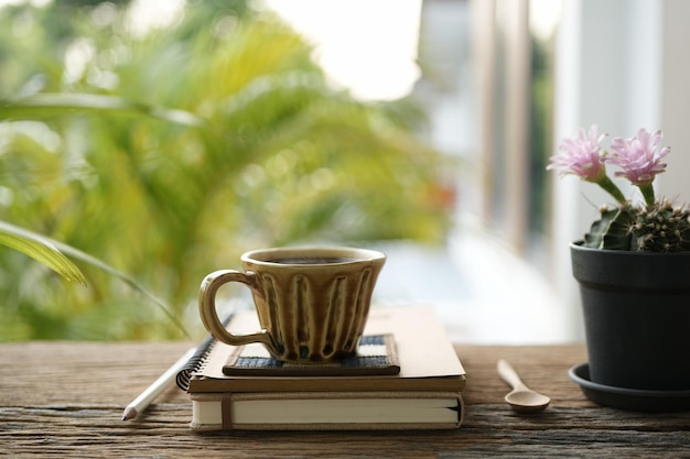コーヒーカップとノートブックと屋外でテーブル上のカクタス