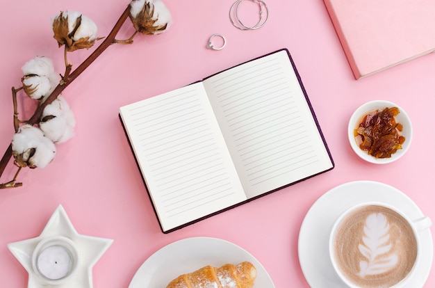 Coffee cup and notebook with croissant and cotton branch