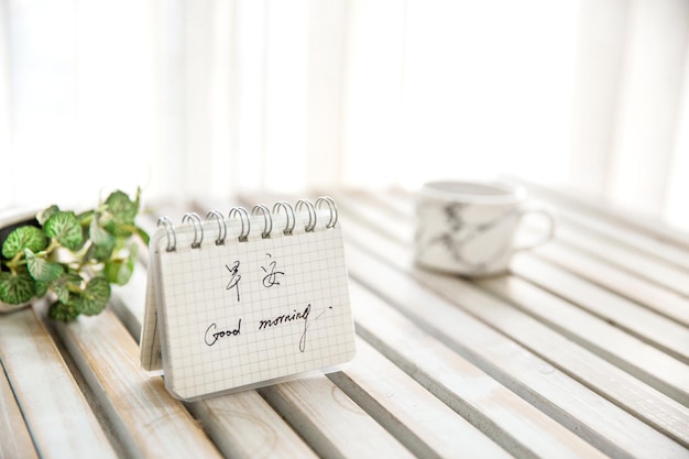 Coffee cup and notepad on white desktop