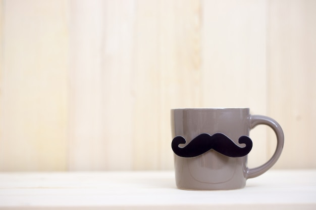 Coffee cup, paper mustache on wooden background with copy space. Happy Father's Day.