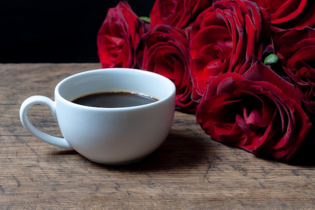 Premium Photo | Coffee cup and red roses behind it.