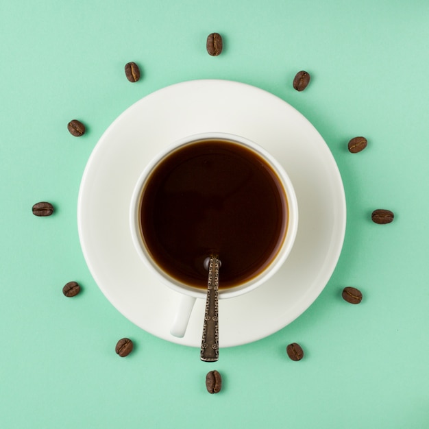 Coffee cup and roasted beans arranged as clock face, top view. Coffee time. Interesting idea energy and refreshment concept.