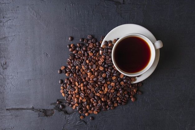 黒の背景にコーヒーカップとローストコーヒー豆