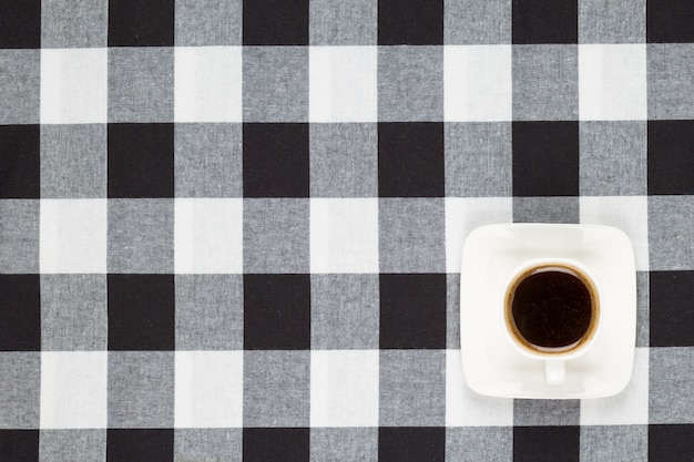 Coffee cup and saucer on checkered tablecloth