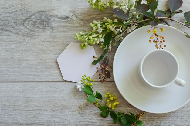 접시 모형과 카피스페이스에 있는 커피 컵 나뭇잎 가지로 둘러싸인 흰색 빈 시트