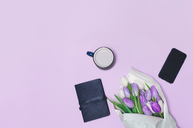 Coffee cup, spring tulip flowers and on table. top view.